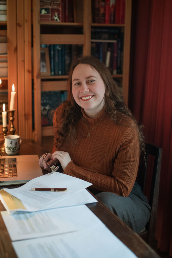 Joy Slaats aan het schrijven aan een tafel met allemaal papieren en haar laptop