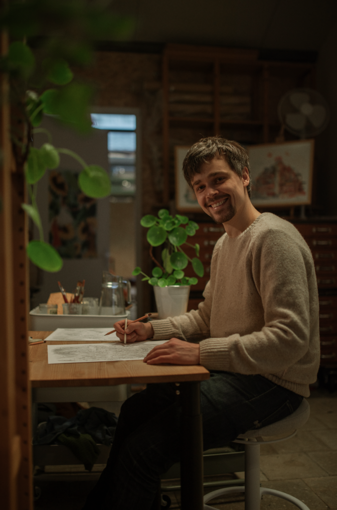 Ralph Zabel tekent aan zijn bureau in zijn atelier.